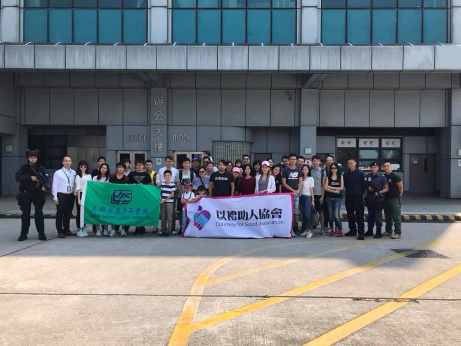 參加者在建築物外手持協會橫額合照。
